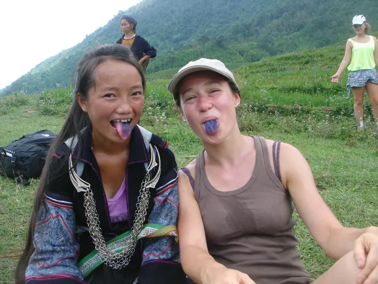 Sapa Sisters guide Little Chi and her traveler showing their tongues, blue from indigo