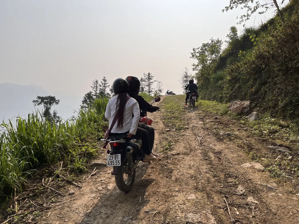 Riders on motorbikes following a rough dirt track along a mountainside in Ha Giang, northern Vietnam
