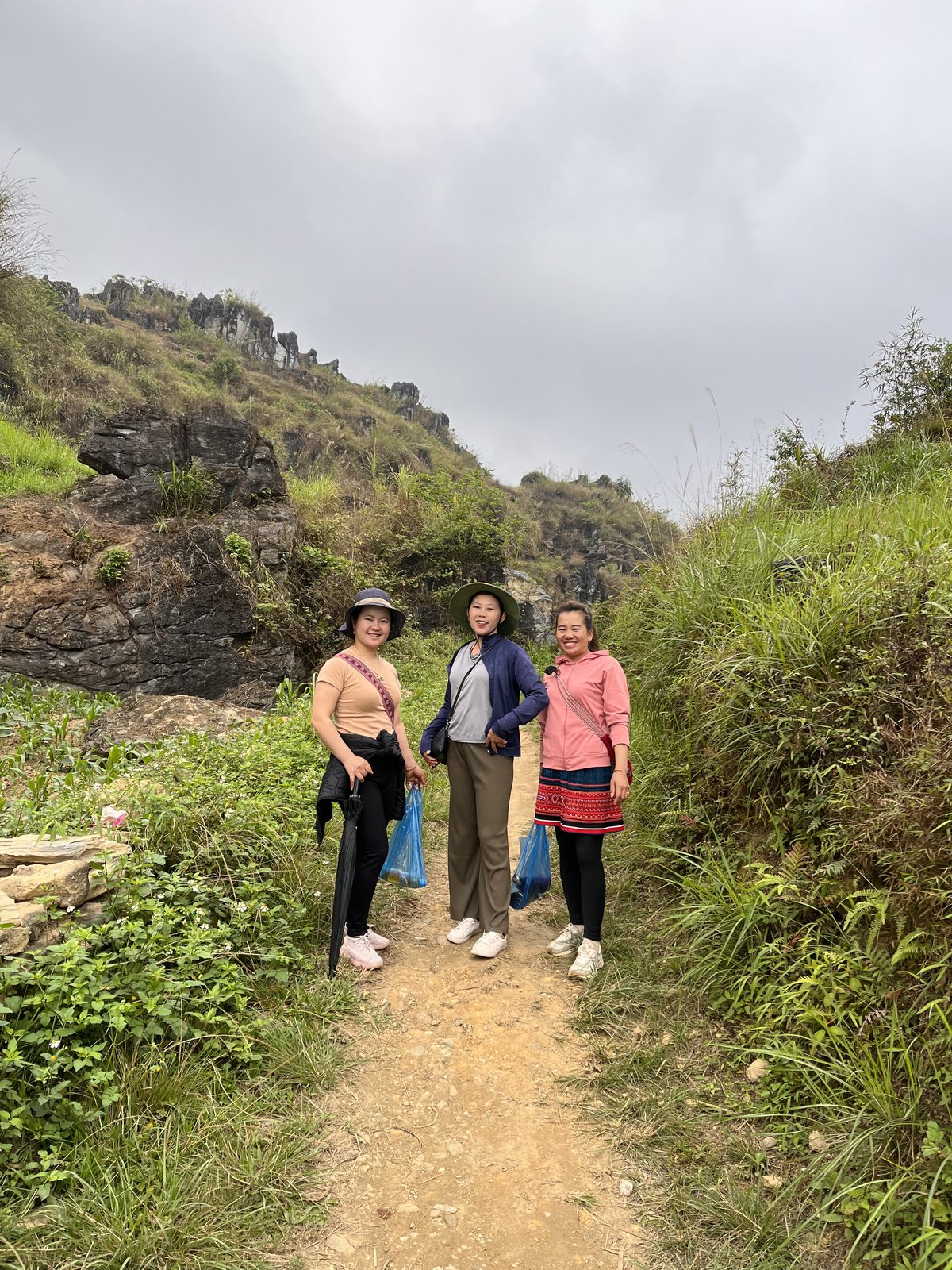 Three Sapa Sisters guides on a dirt trail below limestone cliffs in Ha Giang, northern Vietnam